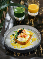 Delicious toast with egg Benedict or poached egg, black caviar, shrimps and microgreens on plate on...