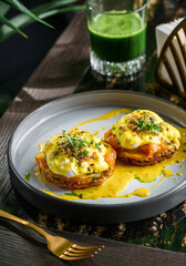 Delicious pancake with slice of salmon, eggs Benedict or poached eggs and sesame and microgreens on plate on marble table with smoothie. Healthy breakfast food, diet, top view