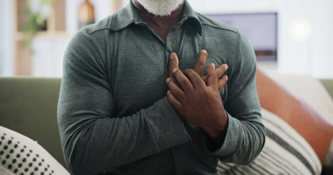 Heart attack, stress and hands of senior man on a sofa with cardiac arrest, emergency or danger at home closeup. Chest pain, anxiety or old person with breathing problem, panic or heartburn crisis