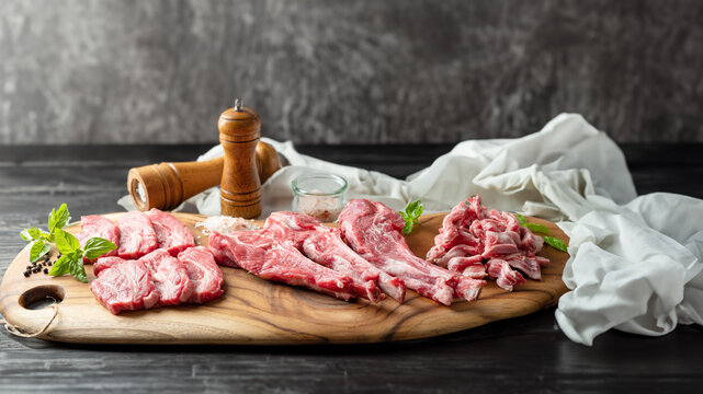 Raw lamb meat in various parts on a wooden plate
