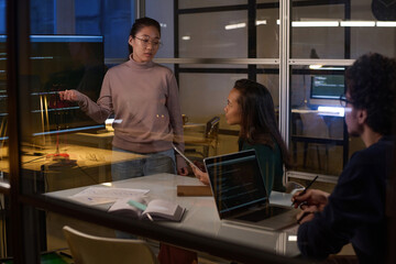 Young Asian programmer working on code together on code at workplace in IT company office late in evening