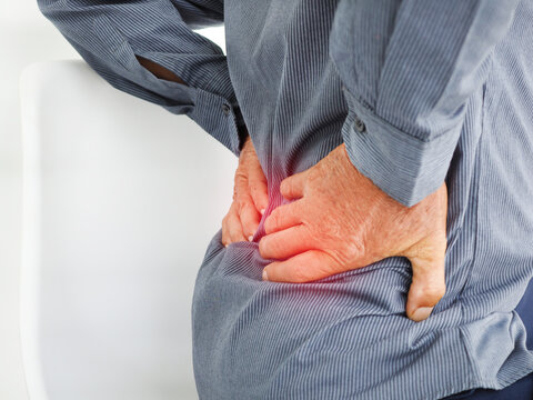 Old man suffering of backache, touching back with hand. Health care concept.