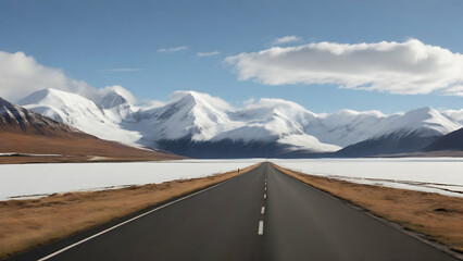 Scenery of a long straight road leading towards a snow capped mountain.