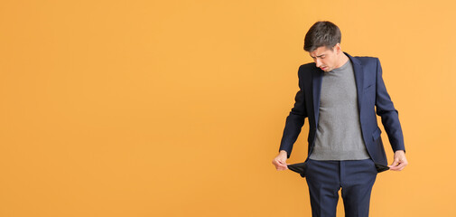 Stressed man with empty pockets on color background. Bankruptcy concept