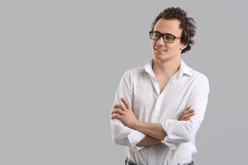 Young businessman in eyeglasses on grey background