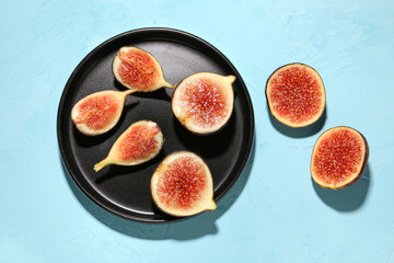 Plate with cut fresh figs on blue background