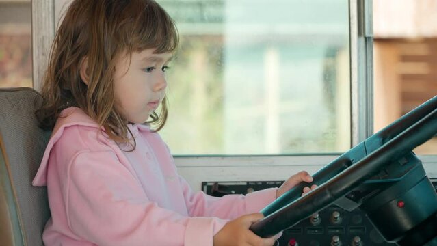 Active Toddler Girl Turns Steering Wheel of Old Bus and Beeping While Sitting in Driver's Seat. Preschool Kid Pretends to Drive Real Bus in Summer - slow motion