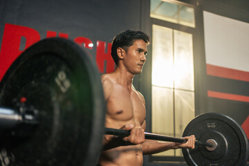 Asian sportsman slowly lift up weight machine barbell in gym stadium. 