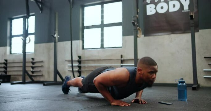 Man, fitness and push ups in workout, exercise or endurance on floor for strength at gym. Active male person, bodybuilder or athlete lifting body weight in muscle gain, chest or biceps at health club