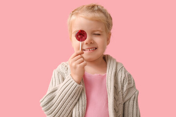Cute little girl with sweet lollipop on pink background
