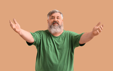 Mature man opening arms for hug on color background