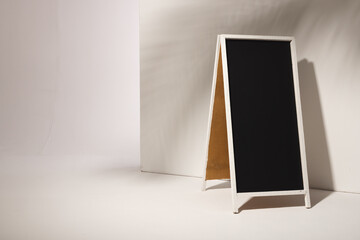 A blank sandwich board sign stands ready for advertising messages, with copy space