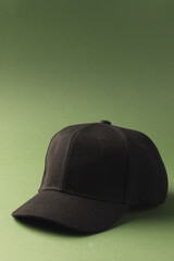 A plain black baseball cap is positioned against a green background, with copy space