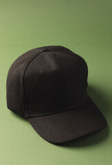 A black baseball cap is positioned against a green background, with copy space