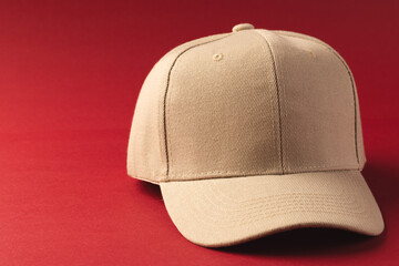 A beige baseball cap is positioned against a red background, with copy space