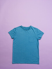 A blue t-shirt is laid out flat against a pink background, with copy space