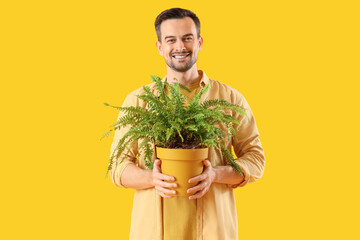Young man with plant on yellow background