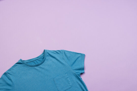 Fototapeta A blue t-shirt is laid out on a purple background, with copy space