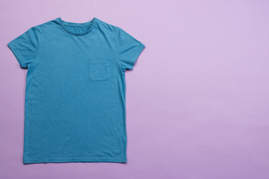Fototapeta A plain blue t-shirt is laid out on a purple background, with copy space