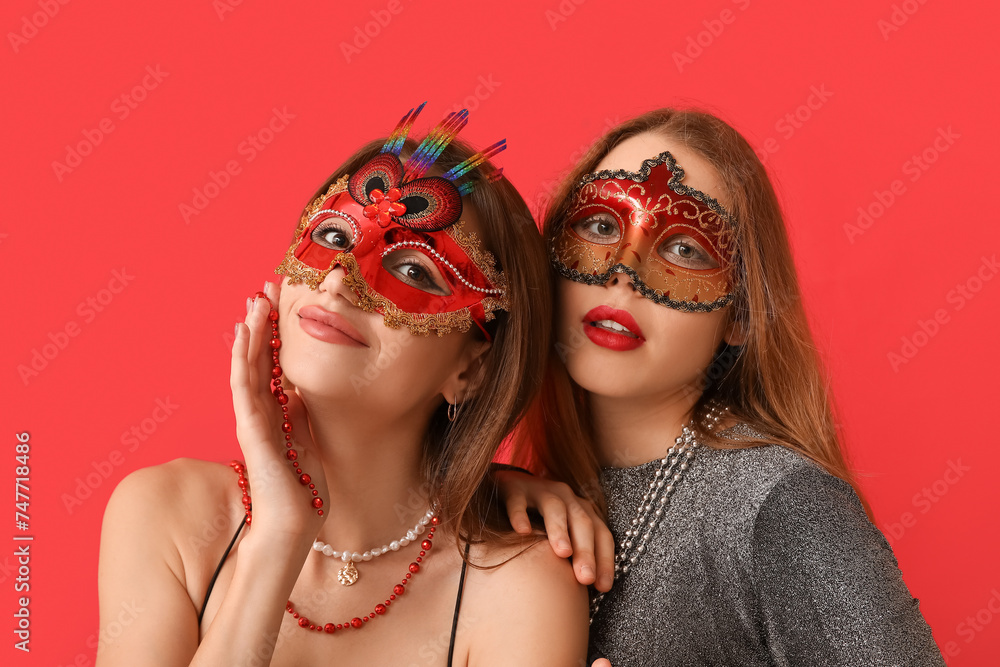 Wall mural pretty young women in carnival masks on red background