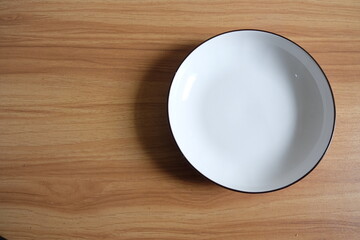 white empty ceramic plate on a wooden table 