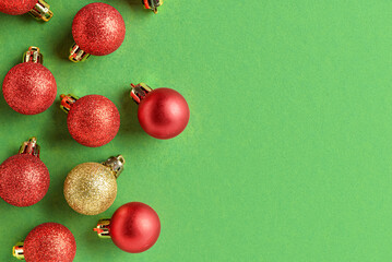 One golden Christmas ball among red ones on green background. Concept of uniqueness