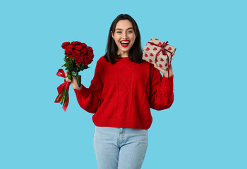 Beautiful young happy woman with gift box and bouquet of roses on blue background. Valentine's Day...