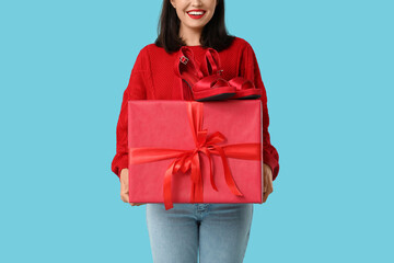 Beautiful young woman with gift box and stylish high heels on blue background. Valentine's Day...