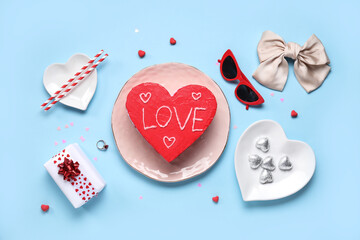 Heart-shaped bento cake with gift box, chocolate candies and ring on blue background. Valentine's...