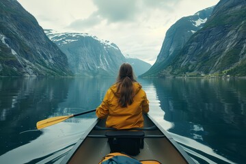 Rear view of a young woman paddling a canoe through calm waters Surrounded by majestic fjords Capturing a moment of solitude and adventure - obrazy, fototapety, plakaty
