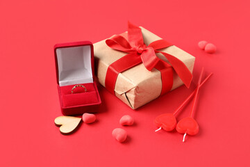 Composition with engagement ring, gift box and decor for Valentine's Day celebration on red...
