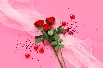 Composition with red rose flowers, candies and tulle fabric on pink background. Valentine's Day...