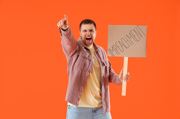 Protesting young man holding placard with word IMPEACHMENT on orange background