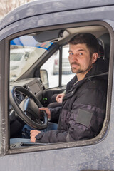 young handsome man driving in the cab of a large truck