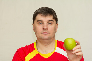 young handsome man holding a green apple in his hands