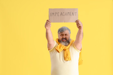 Protesting mature man holding placard with word IMPEACHMENT on yellow background