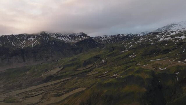 Aerial landscape view of icelandic mountain peaks covered in melting snow, on a cloudy evening