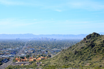 High rise buildings of Phoenix downtown in the Valley of the Sun with a backdrop of South Mountains as seen from North Mountain Park hiking trails on a sunny Spring morning, Arizona