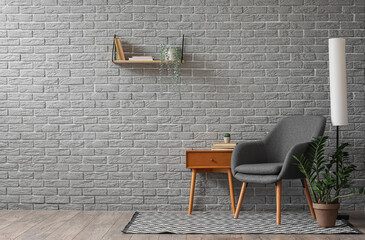 Interior of living room with armchair, lamp and coffee table near brick wall