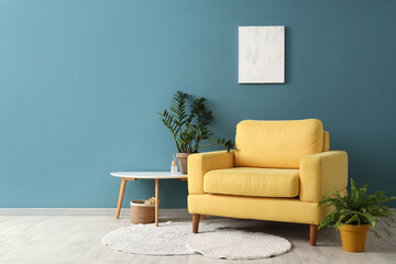 Interior of living room with armchair and picture near blue wall