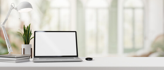 A desk with a laptop mockup set against the blurred background of a modern home office.