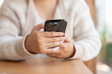 A cropped shot of a woman responding to messages on her smartphone while relaxing in a cafe.