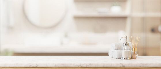 Toiletries and empty space on a white marble tabletop in a modern bright and clean bathroom.