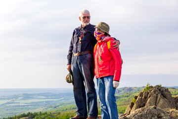 happy mature married couple traveling through the Ural mountains on a summer day