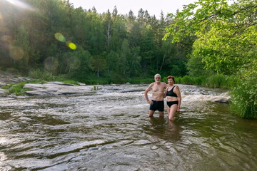 Fototapeta na wymiar sports elderly couple bathes in the mountain river Sakmara in the Southern Urals