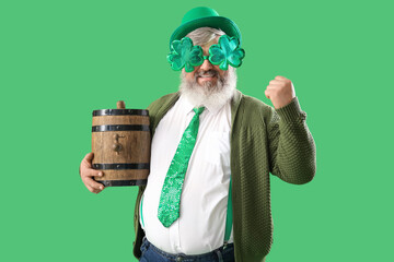 Happy mature man in eyeglasses with barrel on green background. St. Patrick's Day celebration