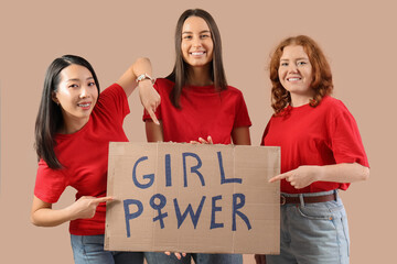 Beautiful young happy women pointing at paper with text GIRL POWER on beige background. Women...
