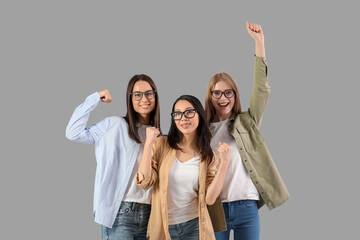 Beautiful young happy women with clenched fists on grey background. Women history month