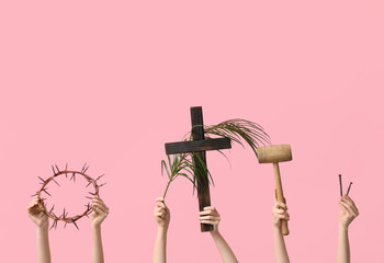 Female hands with wooden cross, crown of thorns and palm leaf on pink background. Good Friday...