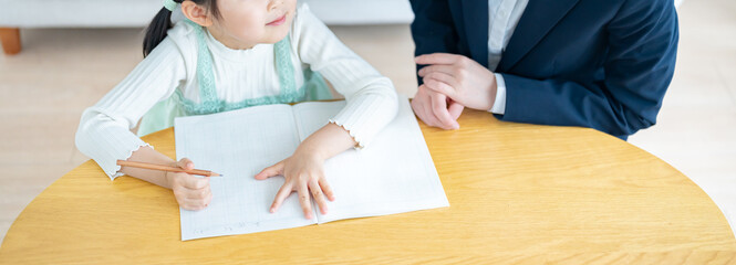 部屋で子供に勉強を教えるスーツを着た女性